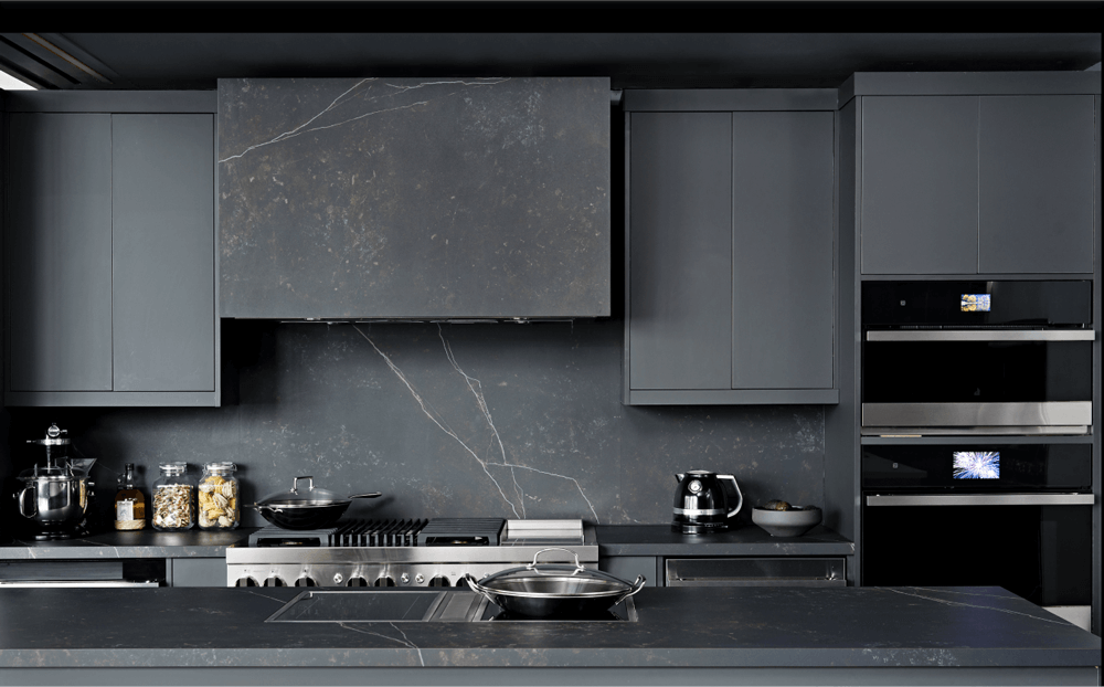 A JennAir Induction Cooktop installed in a dark, modern kitchen with other JennAir Brand appliances. 